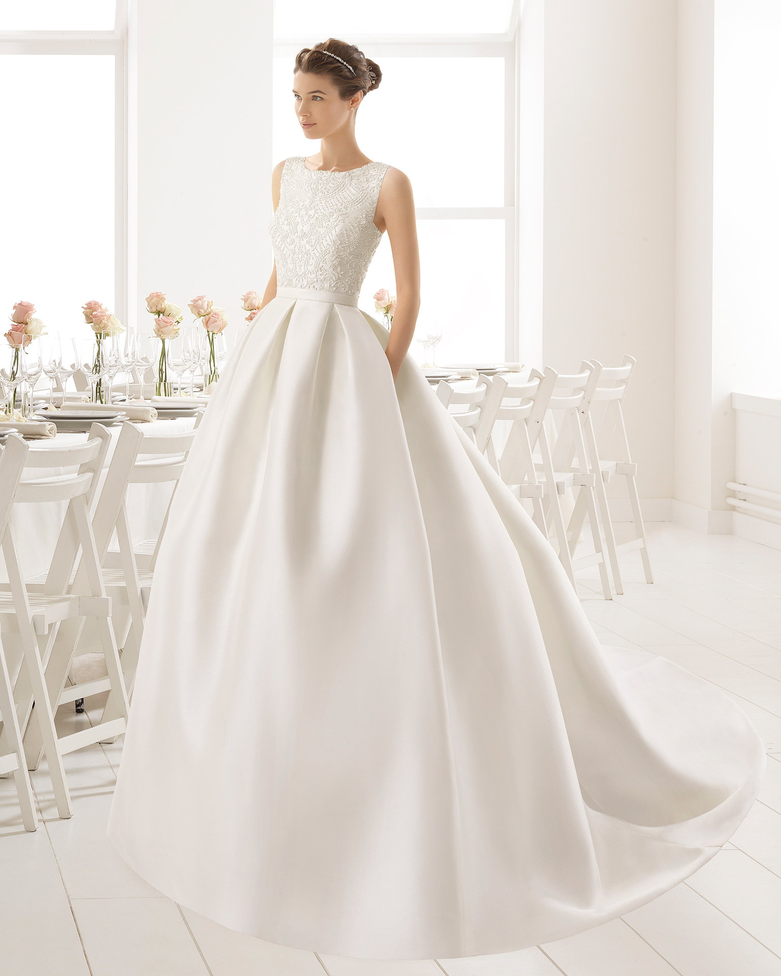 Robe de mariée classique de couture en mikado avec corsage brodé de pierreries et jupe en mikado, col bateau et dos nu avec nœuds, de couleur naturelle.