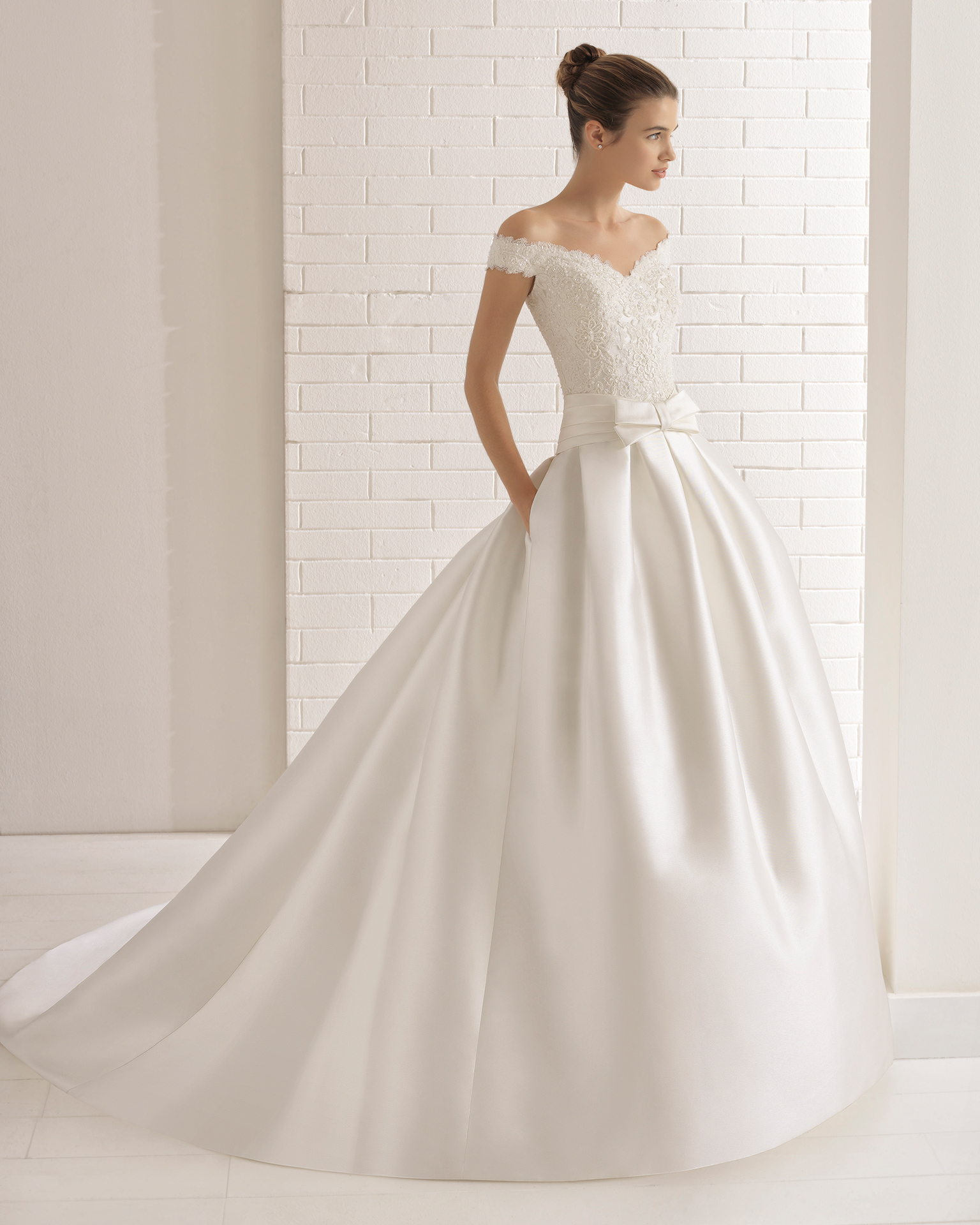 A-line beaded lace and mikado wedding dress with off-the-shoulder neckline, pockets and bow at waist.