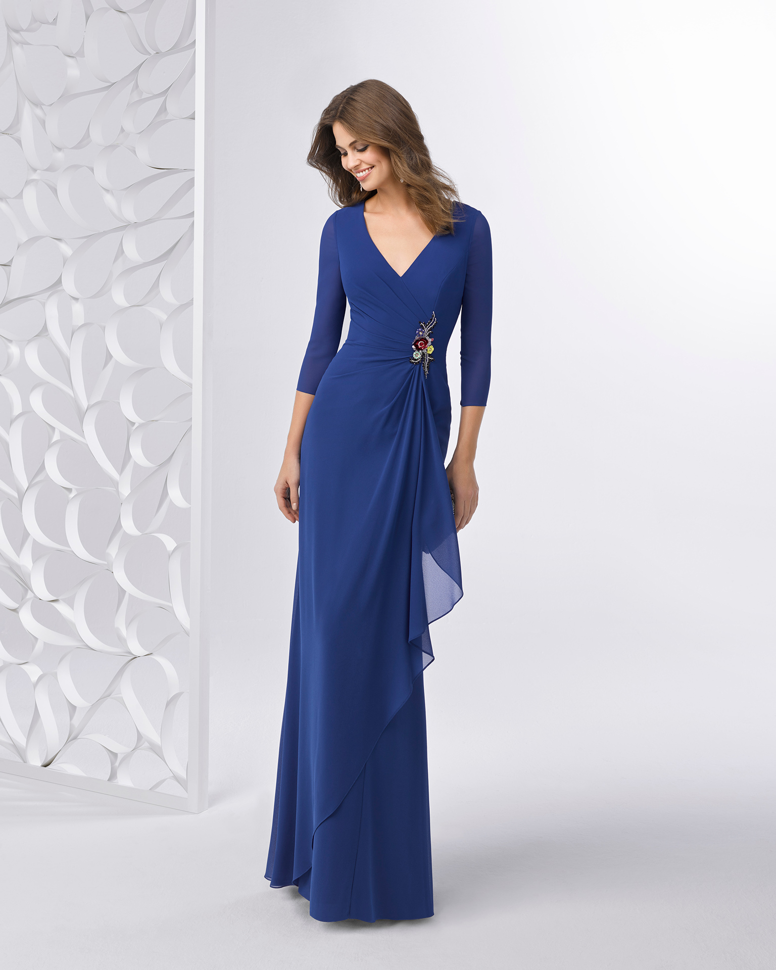 Rochie de cocktail lungă din voal cu strasuri, cu spatele cu efect de bijuterie. Disponibilă în culorile roșu și albastru. Colecția FIESTA AIRE BARCELONA 2018.