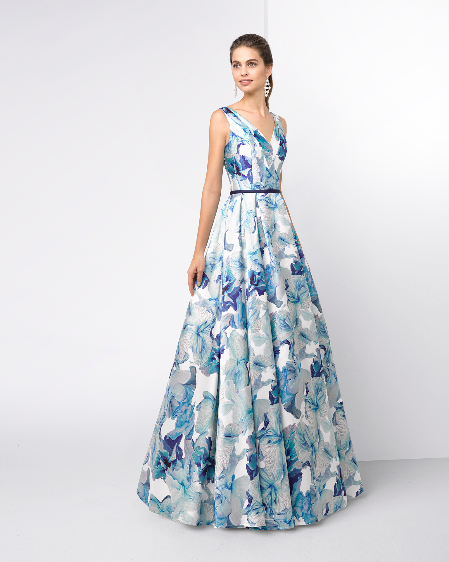 Rochie de cocktail lungă din mikado cu decolteu în V și fustă plisată. Disponibilă în culoarea verde cu imprimeuri. Colecția FIESTA AIRE BARCELONA 2018.