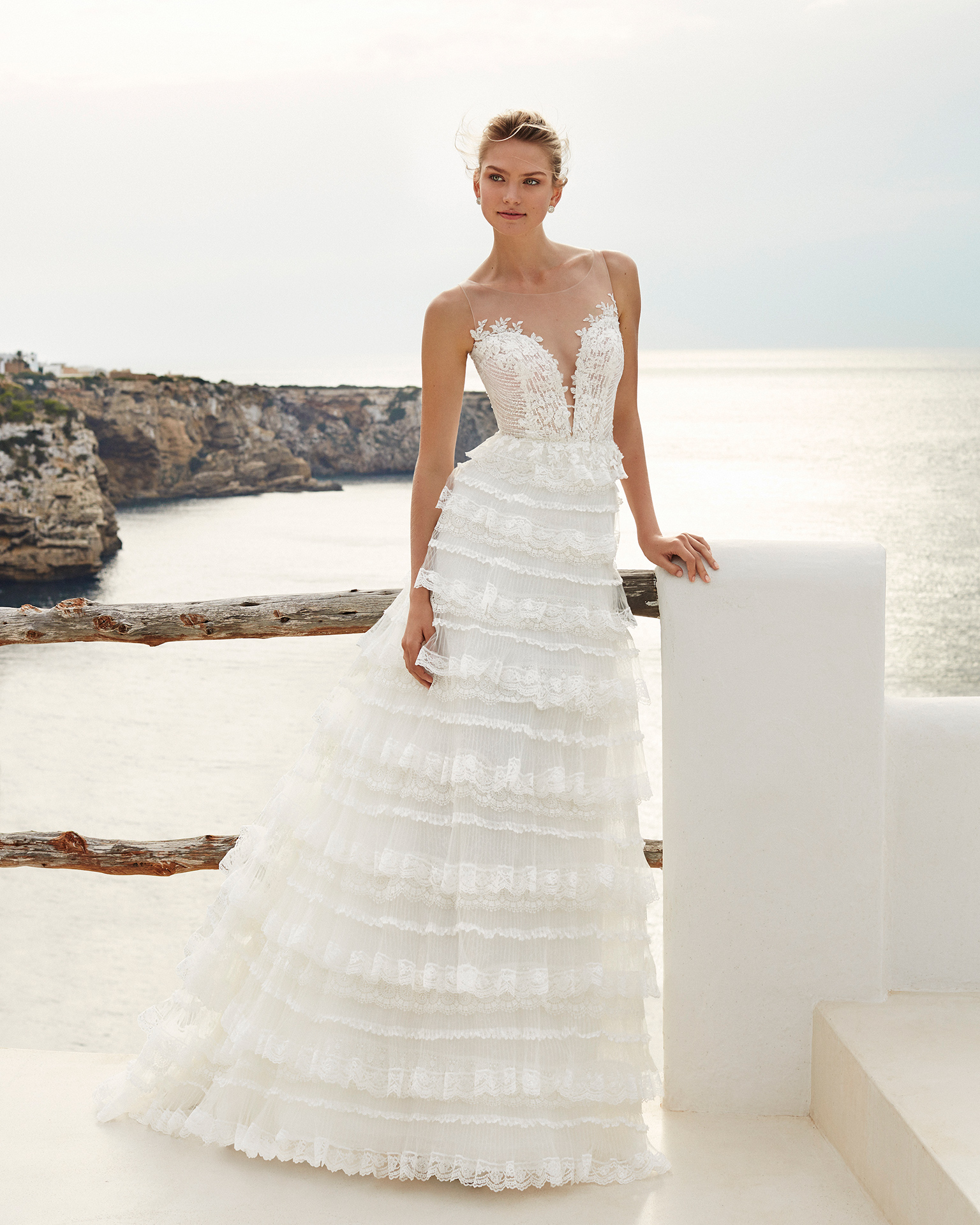 Vestido de novia corte recto de encaje pedrería y tul. Escote deep-plunge con volantes de encaje. Escote profundo y espalda escotada. Disponible en color natural. Colección AIRE BEACH WEDDING 2019.